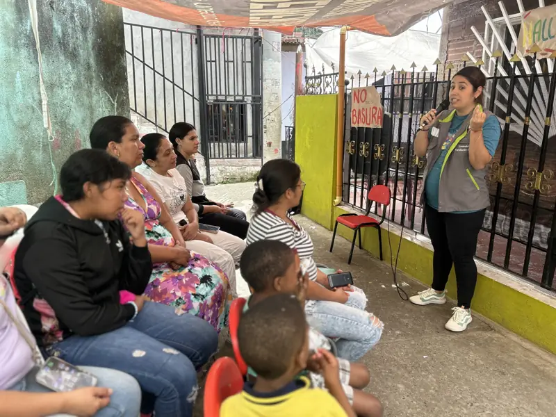 A leader talking with a group of neighbors sitting in a neighborhood street