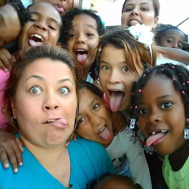 Una voluntaria y varios niños sacando la lengua en una selfie