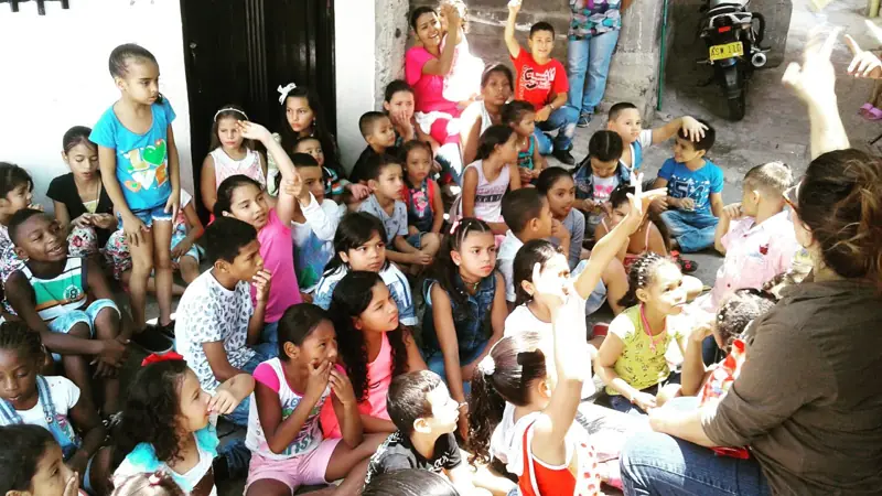 Niños sentados en el piso de una calle, mirando a la cámara
