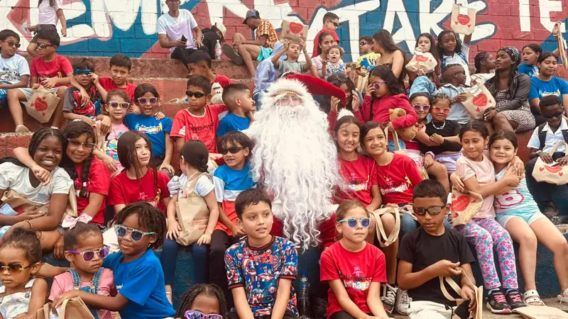 Niños con gafas de sol de colores posando con Papá Noel en unas graderías