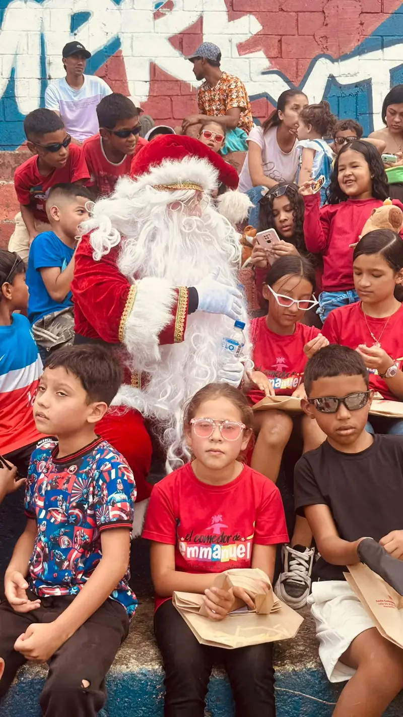 Papá Noel rodeado de niños con camisetas rojas del comedor