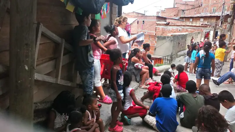 Niños jugando en una calle empinada del barrio, junto a una casa de madera