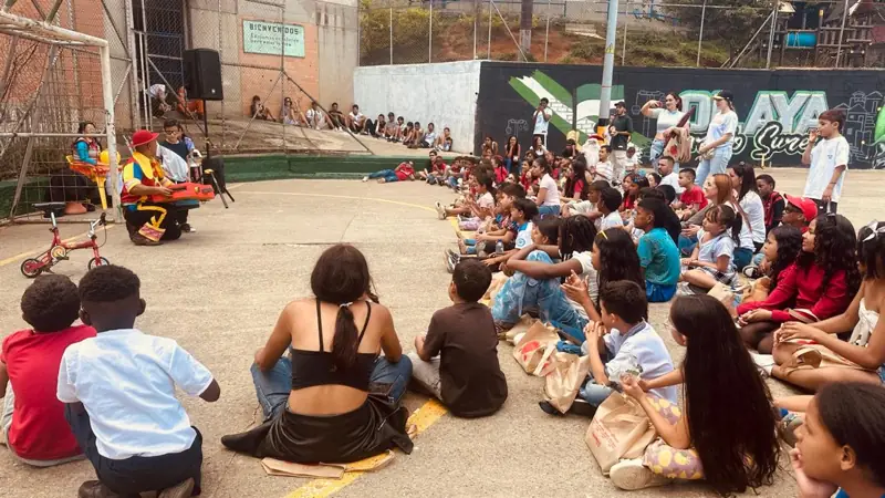 Niños sentados en círculo en una cancha del barrio durante una actividad