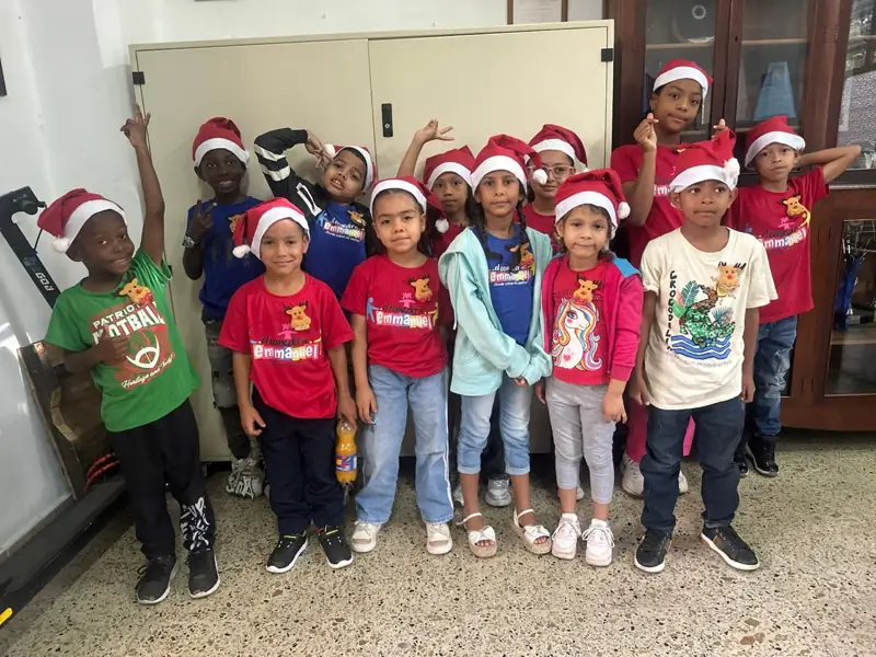 Niños y niñas con gorros de Navidad y camisetas del comedor posando juntos