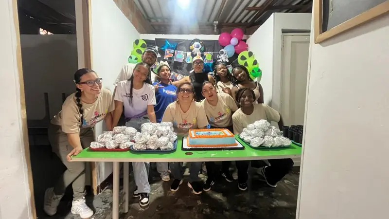 Voluntarias con tortas y regalos en una mesa, en la celebración del cumpleaños del comedor