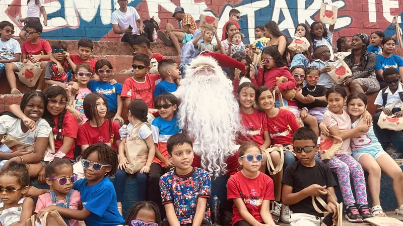 Decenas de niños con gafas de sol de colores posando con Papá Noel