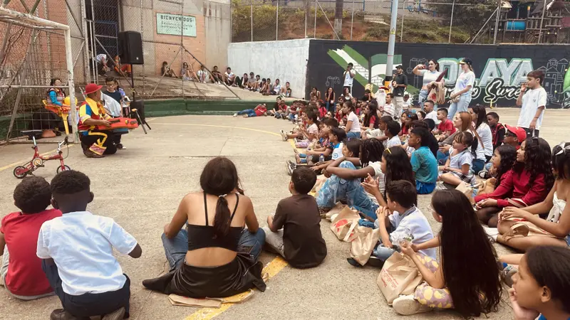 Niños sentados en el piso de una cancha durante una actividad