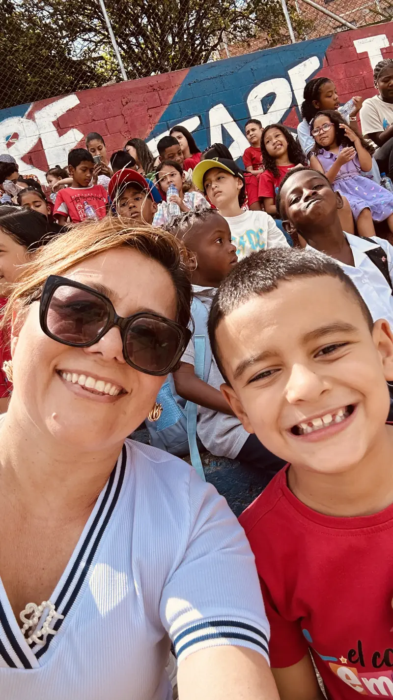 Una voluntaria y un niño sonriendo en una foto con muchos niños detrás
