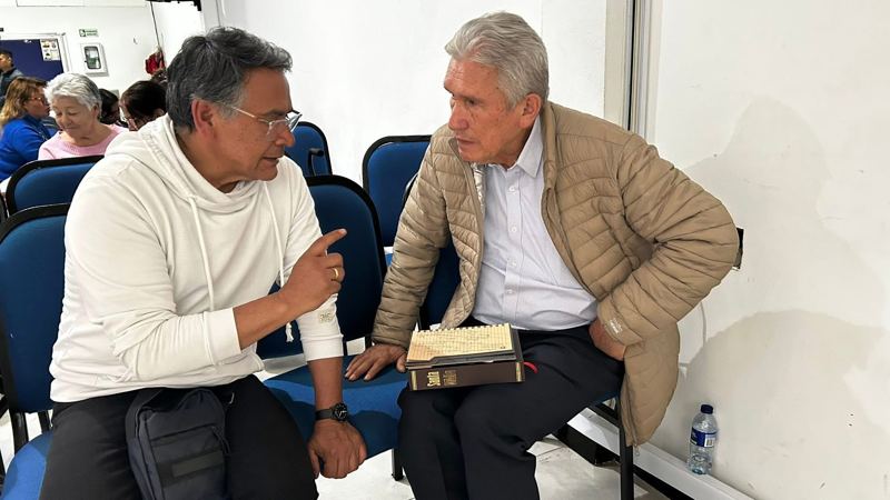 Two men talking, one holding a Bible
