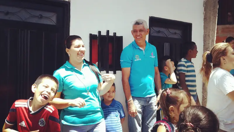 Center volunteers with children and families at the entrance of a house