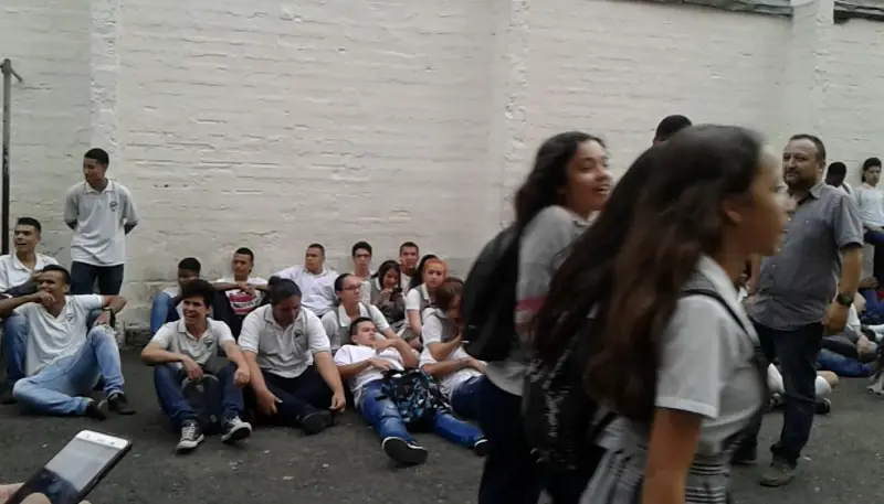 School students sitting on the floor of the yard during an activity