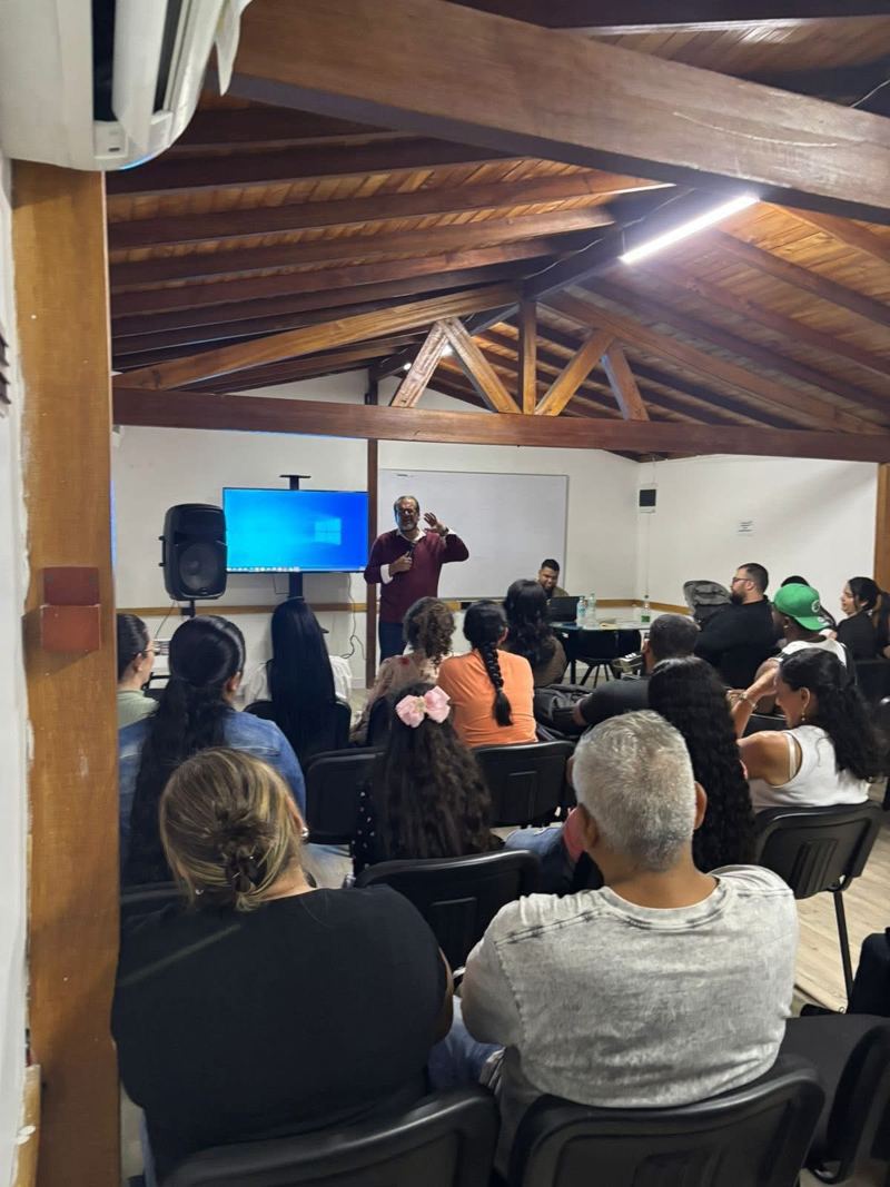 Maestro enseñando a un grupo de adultos en un salón con techo de madera