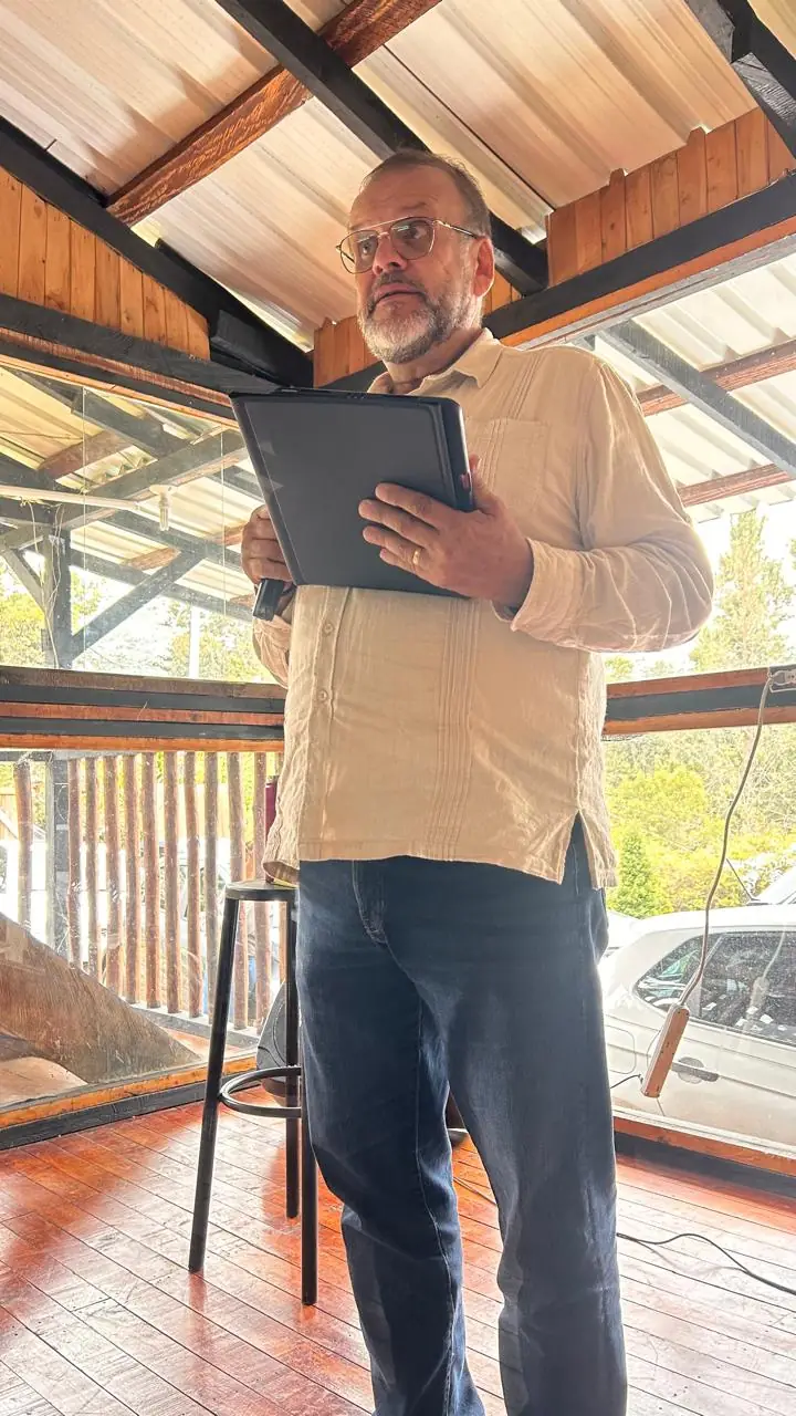 A teacher reading aloud, standing in a room with a wooden ceiling