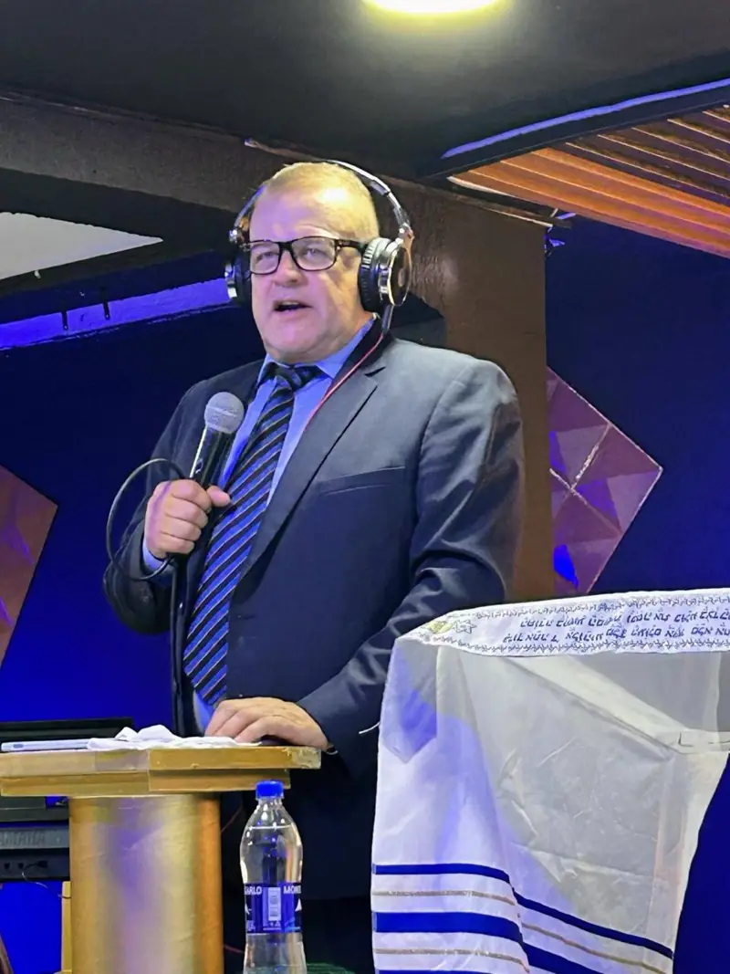 A preacher with headphones and a microphone speaking from the pulpit