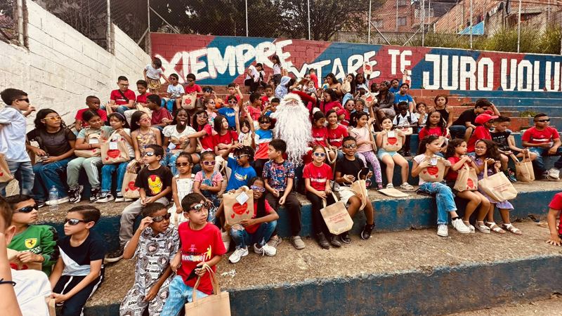 Decenas de niños del comedor con Papá Noel en las graderías de una cancha del barrio