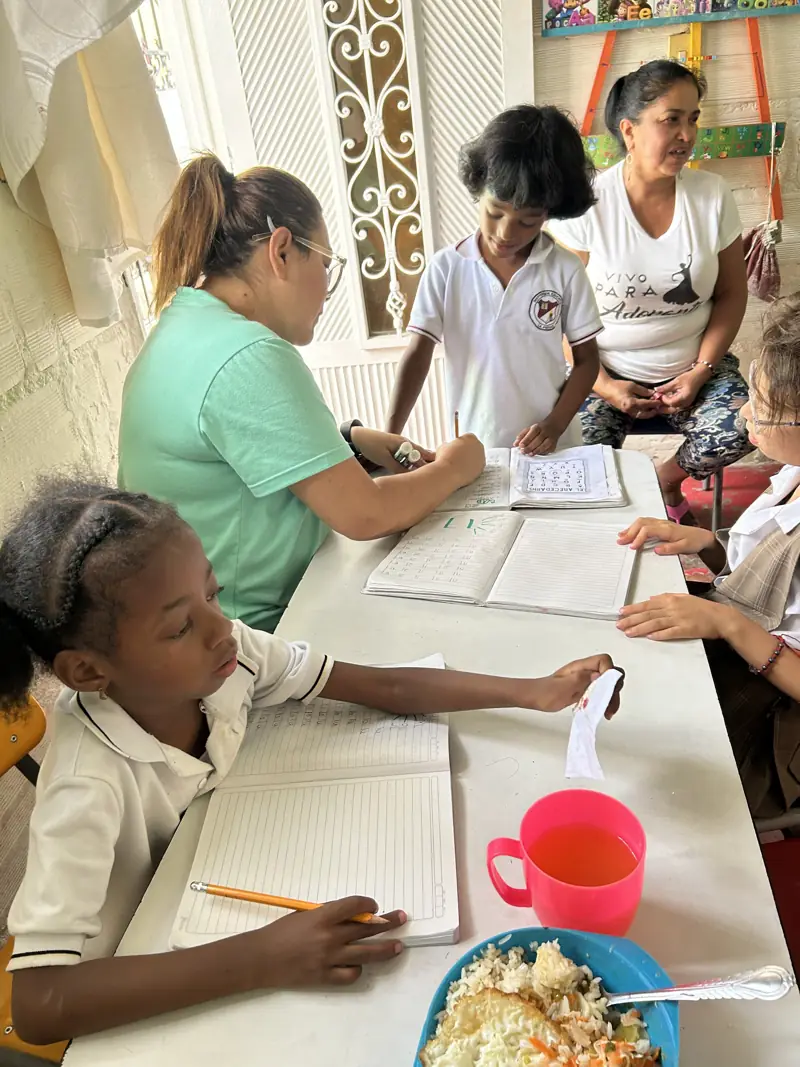 Volunteers helping children with their homework at a table